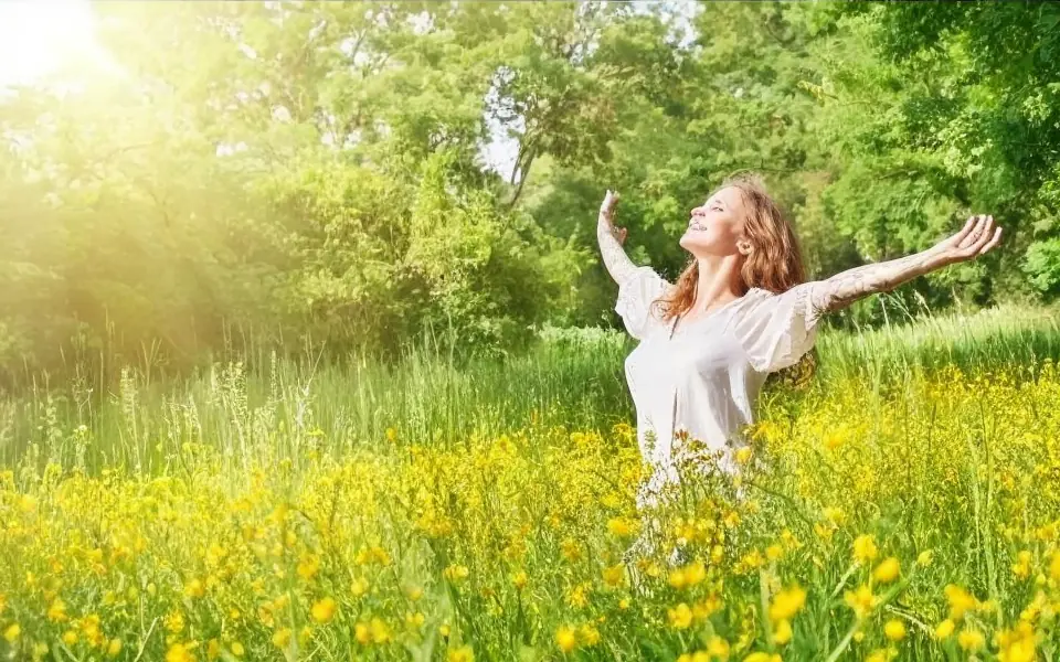 Person with arms outstretched in a field of yellow flowers